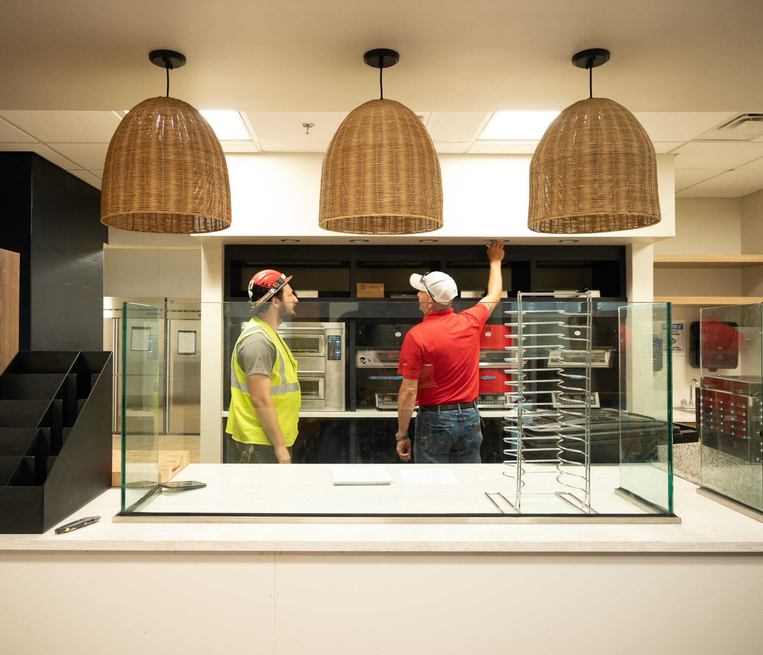 A crew leader and Project Manager examine light fixtures in a nearly complete cafe construction project.